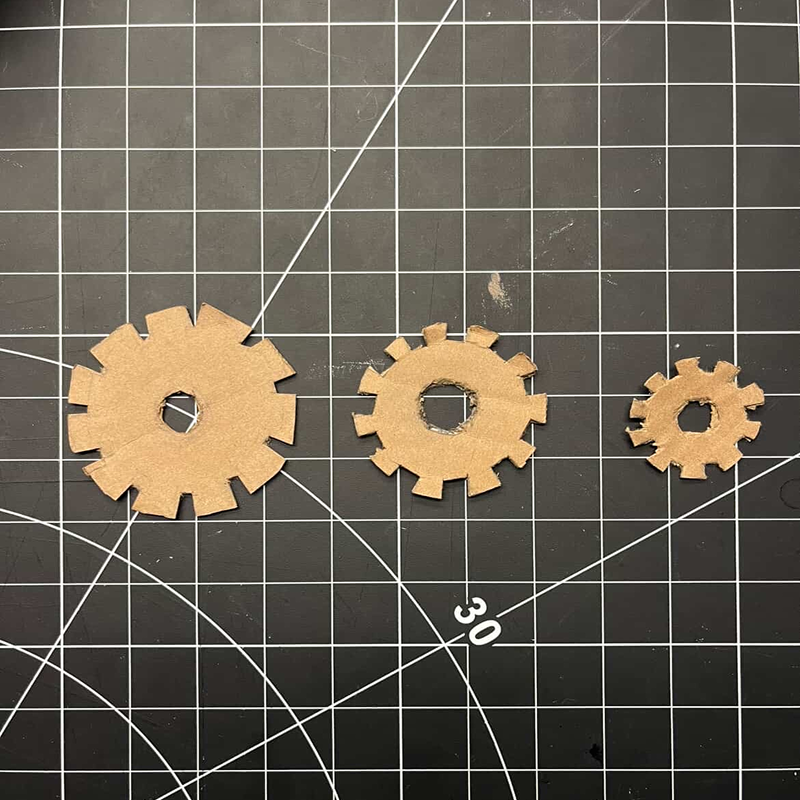 Trimming edges and shaping the cardboard into gear components.